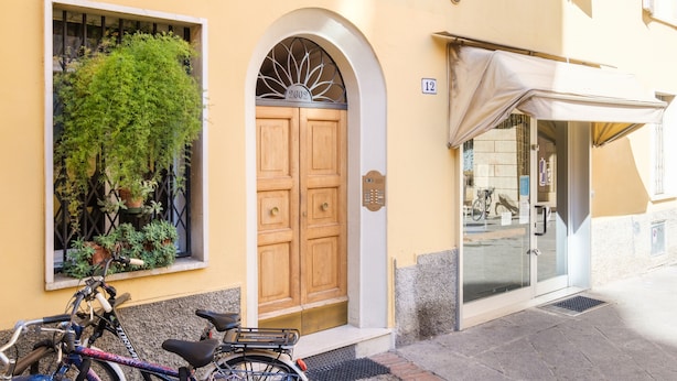 Um edifício com porta de madeira, janela com plantas e bicicleta estacionada na frente.