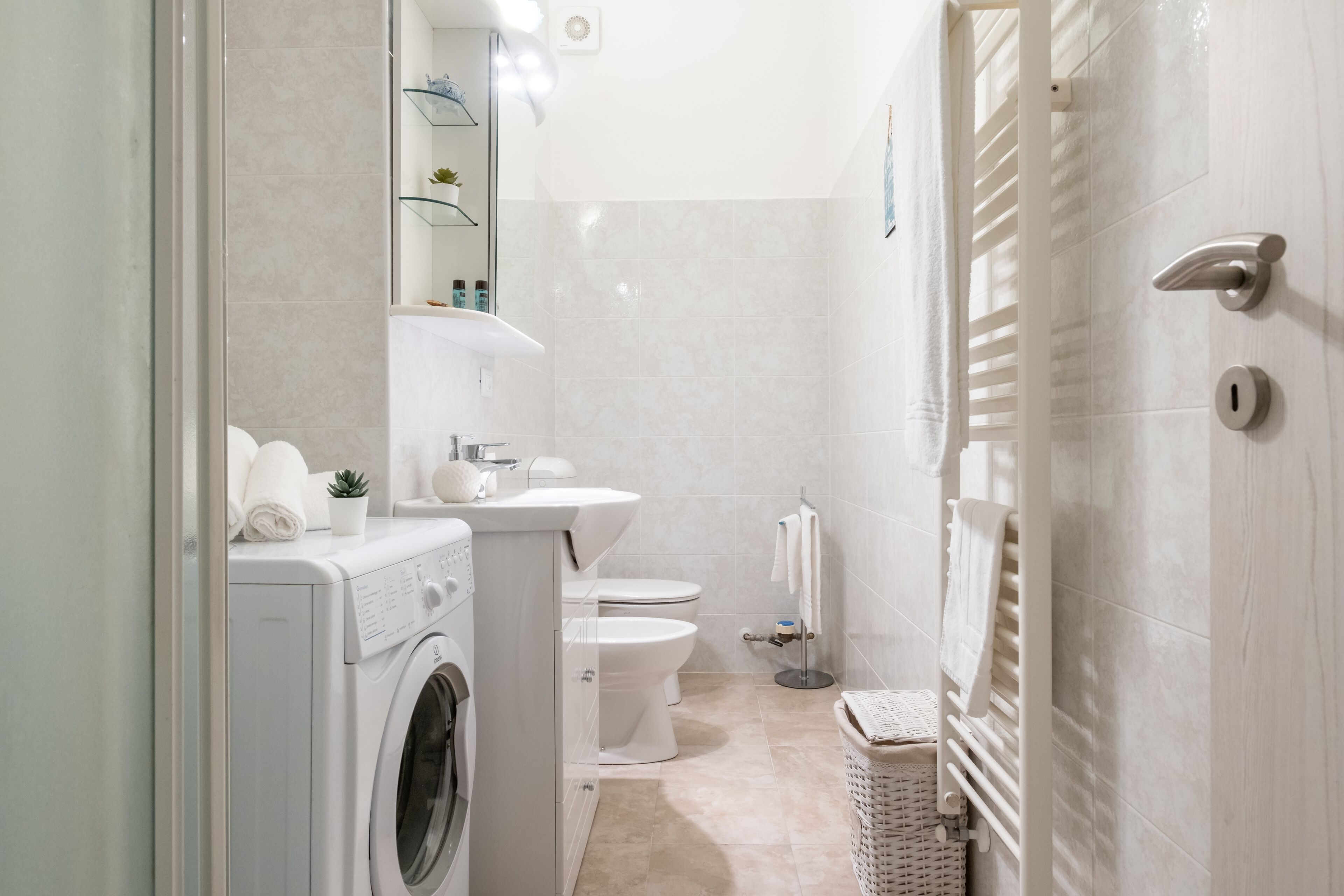 Un baño moderno con lavadora, inodoro y perchero para toallas.