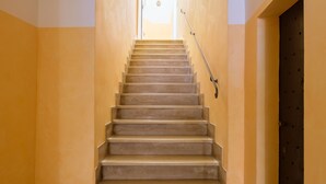 Uma escada com corrimão, que leva a uma porta no topo.