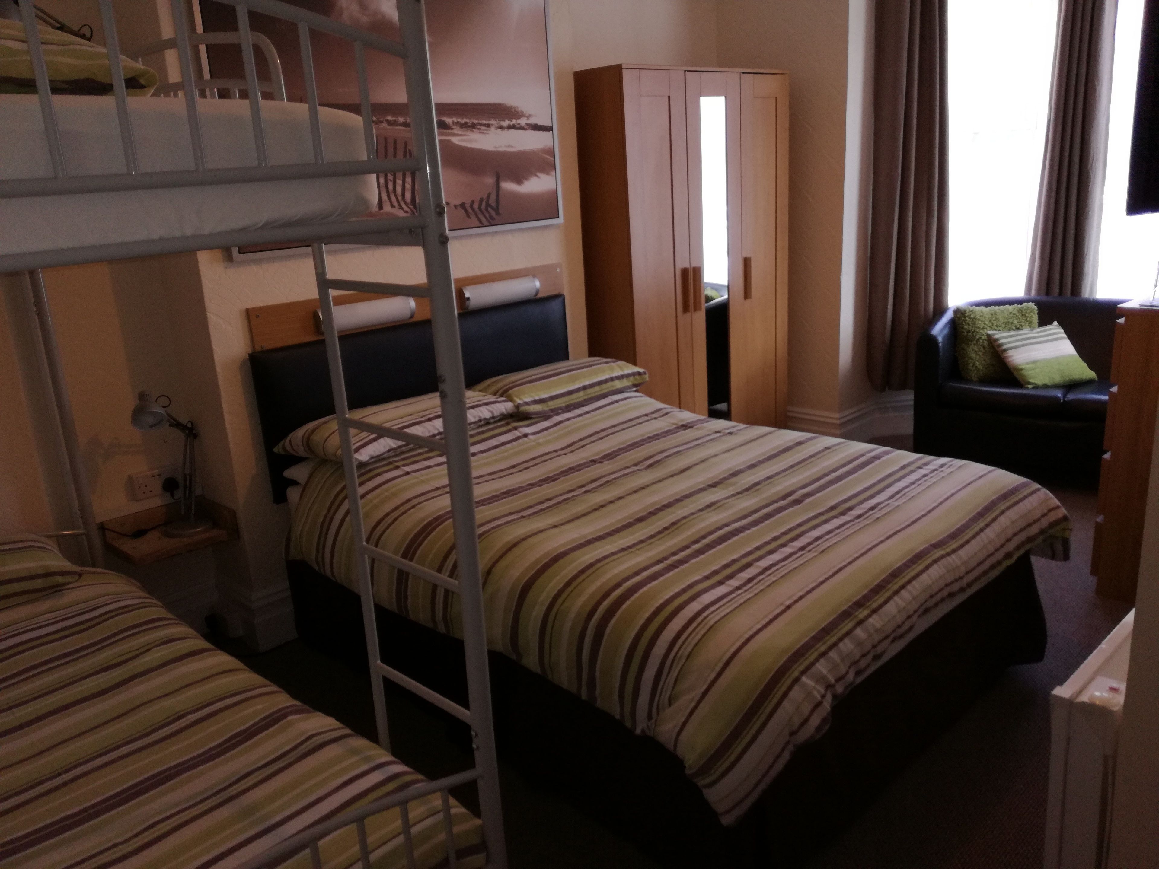 Une chambre d’hôtel avec des lits superposés, une armoire, un bureau et une chaise.