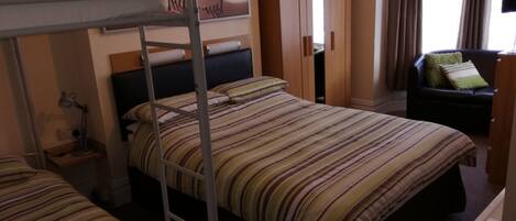 A hotel room with bunk beds, a wardrobe, a desk, and a chair.
