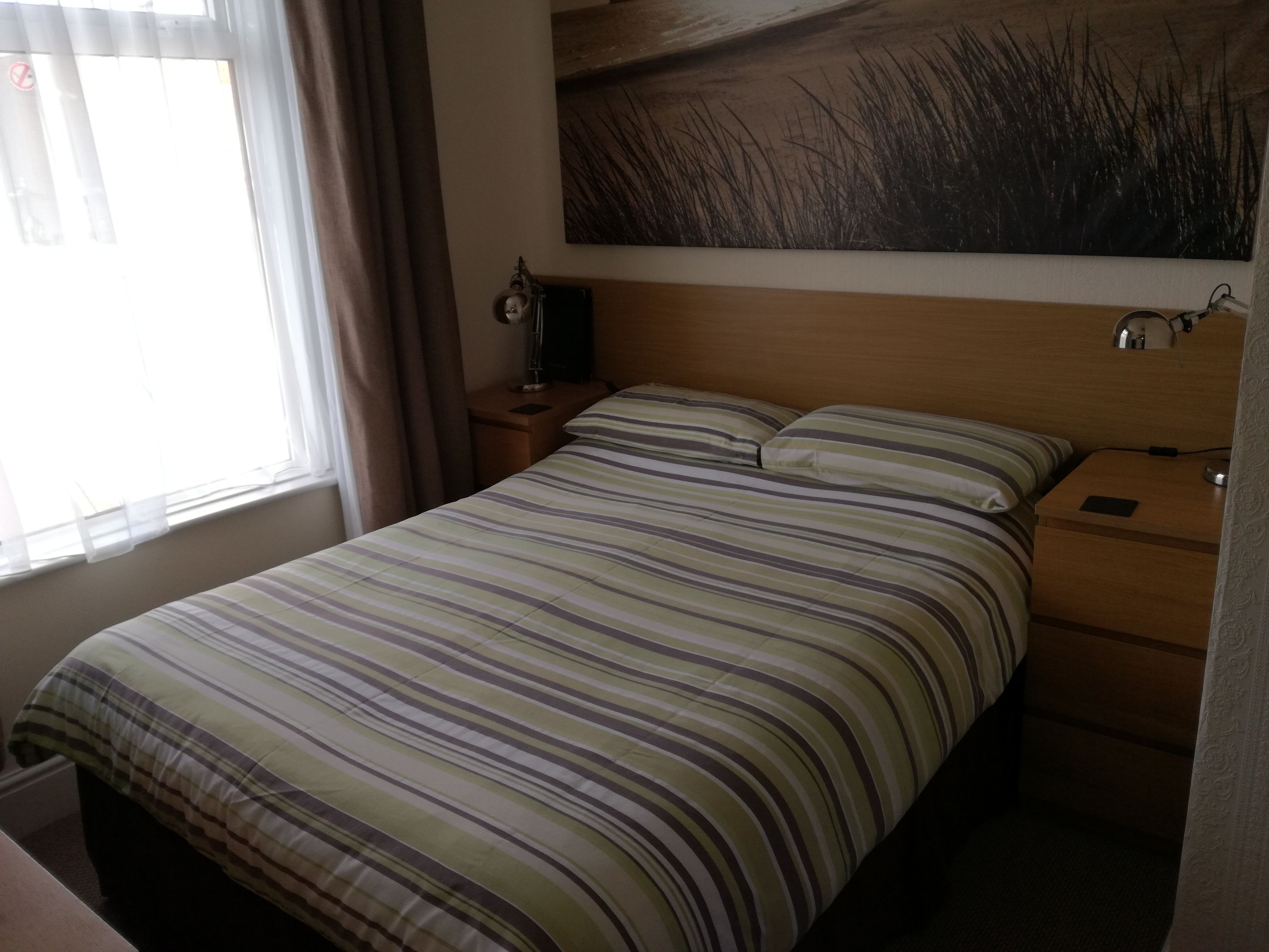 Une chambre d’hôtel avec un lit, une table de chevet, une lampe et un tableau au mur.