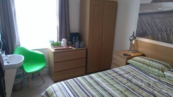 Una habitación de hotel con una cama, un escritorio con una silla, un armario y un baño.