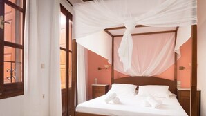 A four-poster bed with white linens and a canopy, wooden headboard, and bedside tables with lamps. - Xenon Apartments (Chania)
