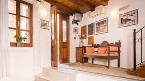 A cozy room with a wooden bench, a small table with a vase, and a staircase leading to another area. - Xenon Apartments (Chania)