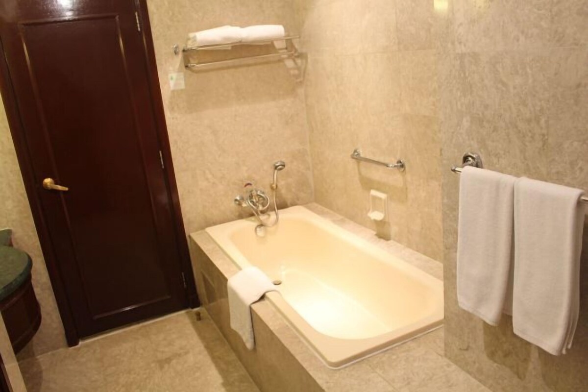 A bathroom with a bathtub, a towel rack, and a door.