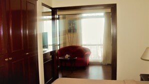 Una habitación de hotel con una puerta de madera, un sofá rojo, una mesita y una cama.