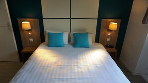Una cama bien hecha con dos almohadas, dos lámparas de noche y un cabecero con diseño de cuadrícula.