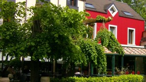Un edificio rojo con toldo verde, un cartel que dice "BAR" y un cartel de "PARK BIERER".