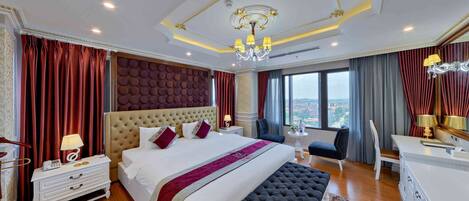 Amplia habitación de hotel con una cama grande, zona de estar y vistas a la ciudad.