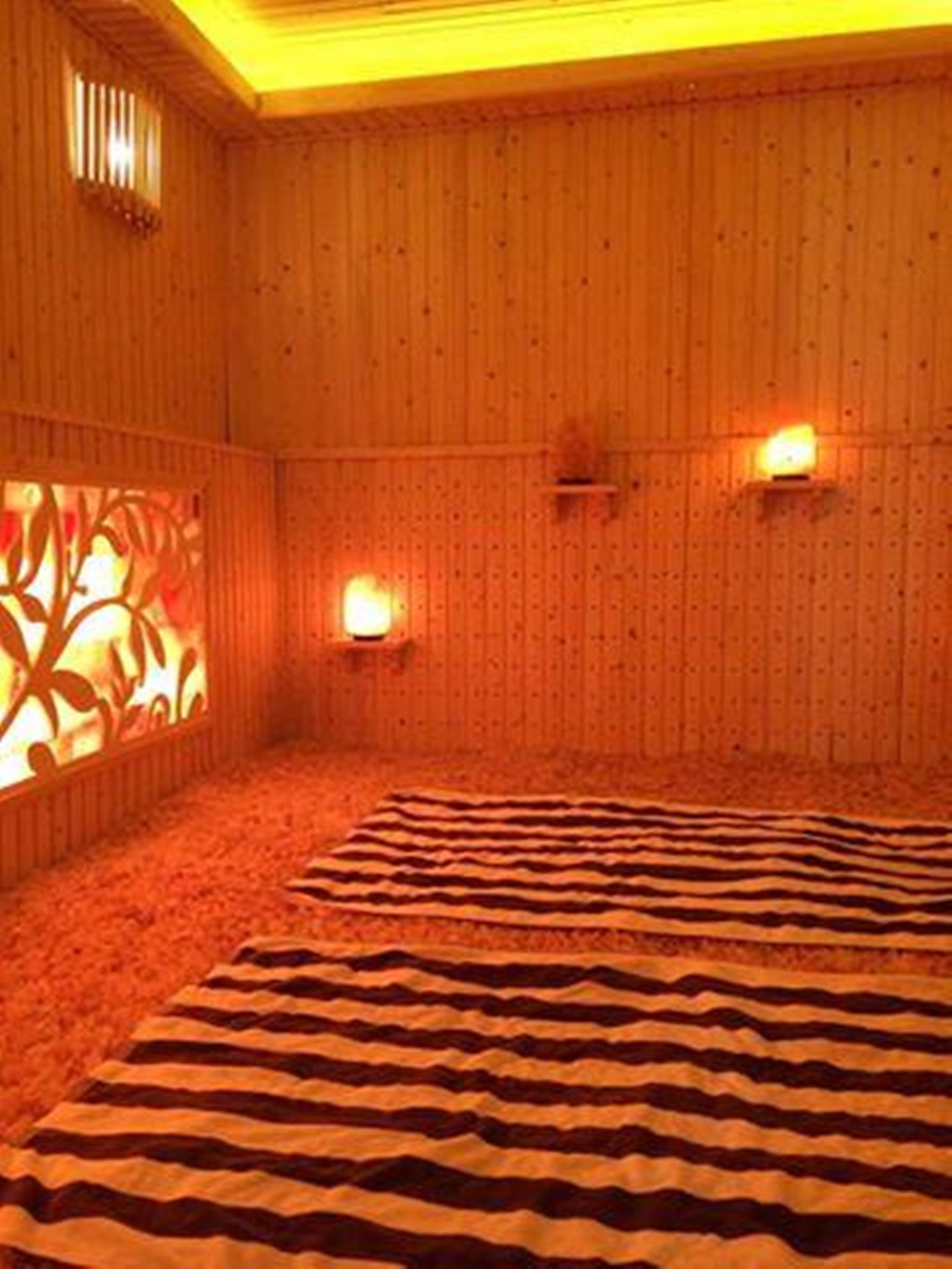 Une pièce aux murs recouverts de lambris en bois, dotée d’un tapis à motifs et de deux appliques murales.