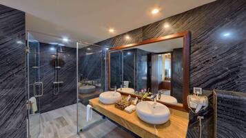 Een moderne badkamer met een douche met glazen wand, twee wastafels en een grote spiegel.