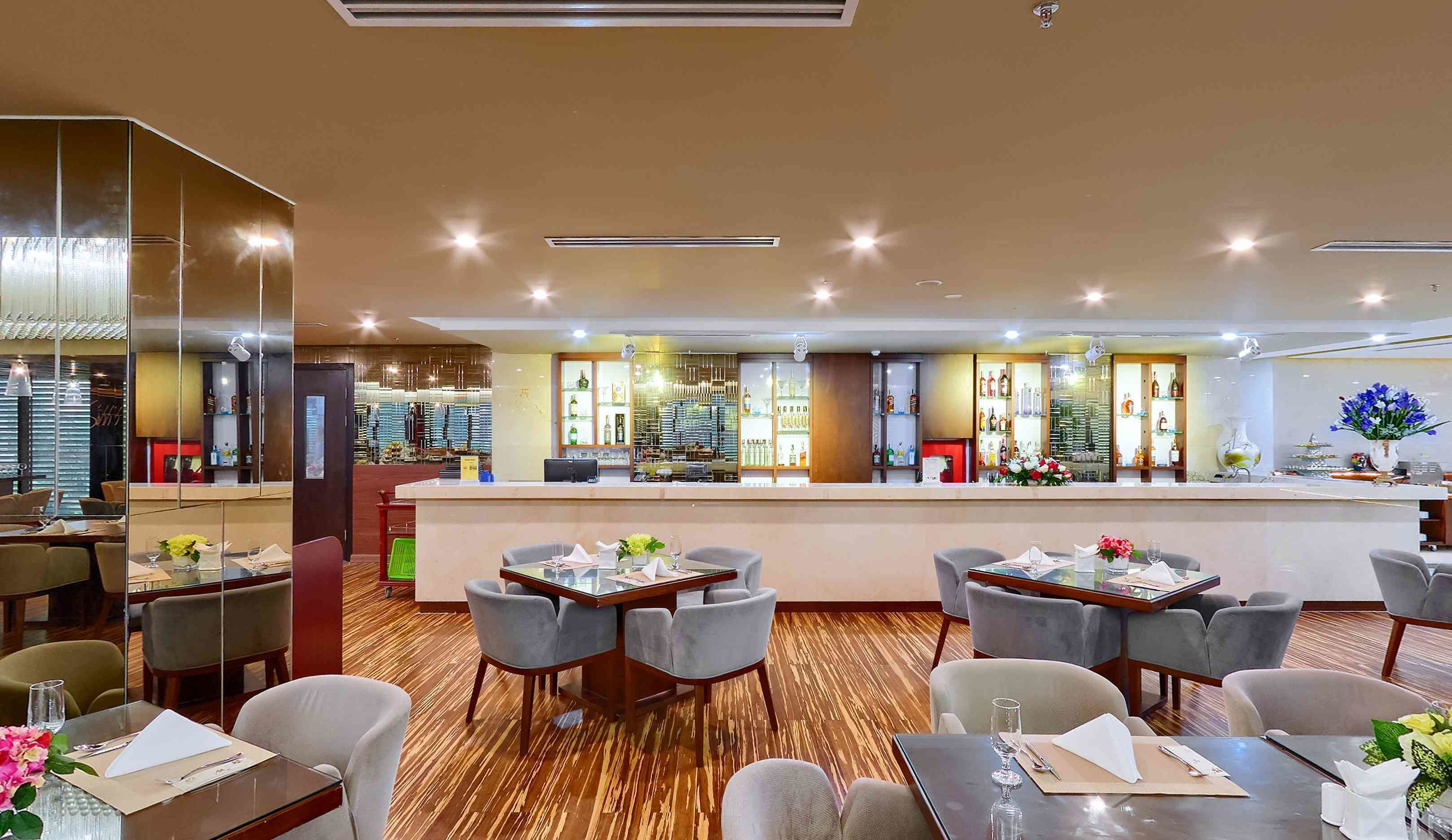 Un vestíbulo de hotel con una zona de bar, mesas y sillas para comer.