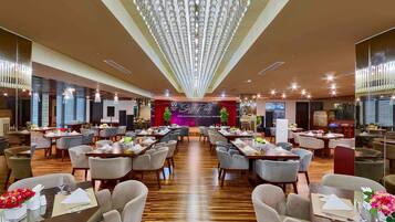 Una amplia sala de conferencias con un escenario, varias mesas y sillas dispuestas para una reunión o evento.