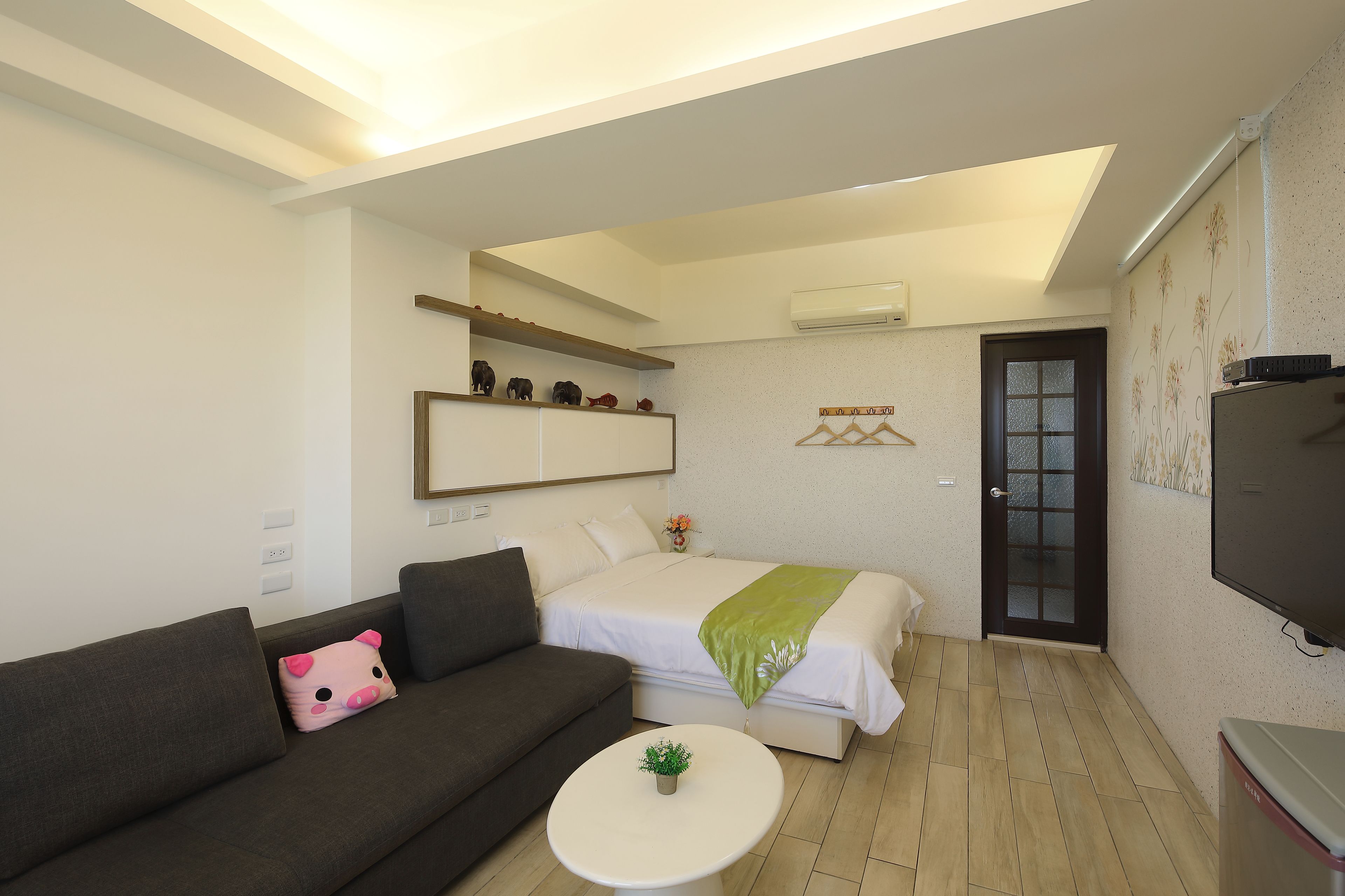 A modern bedroom with a bed, a sofa, a small table, and a TV.