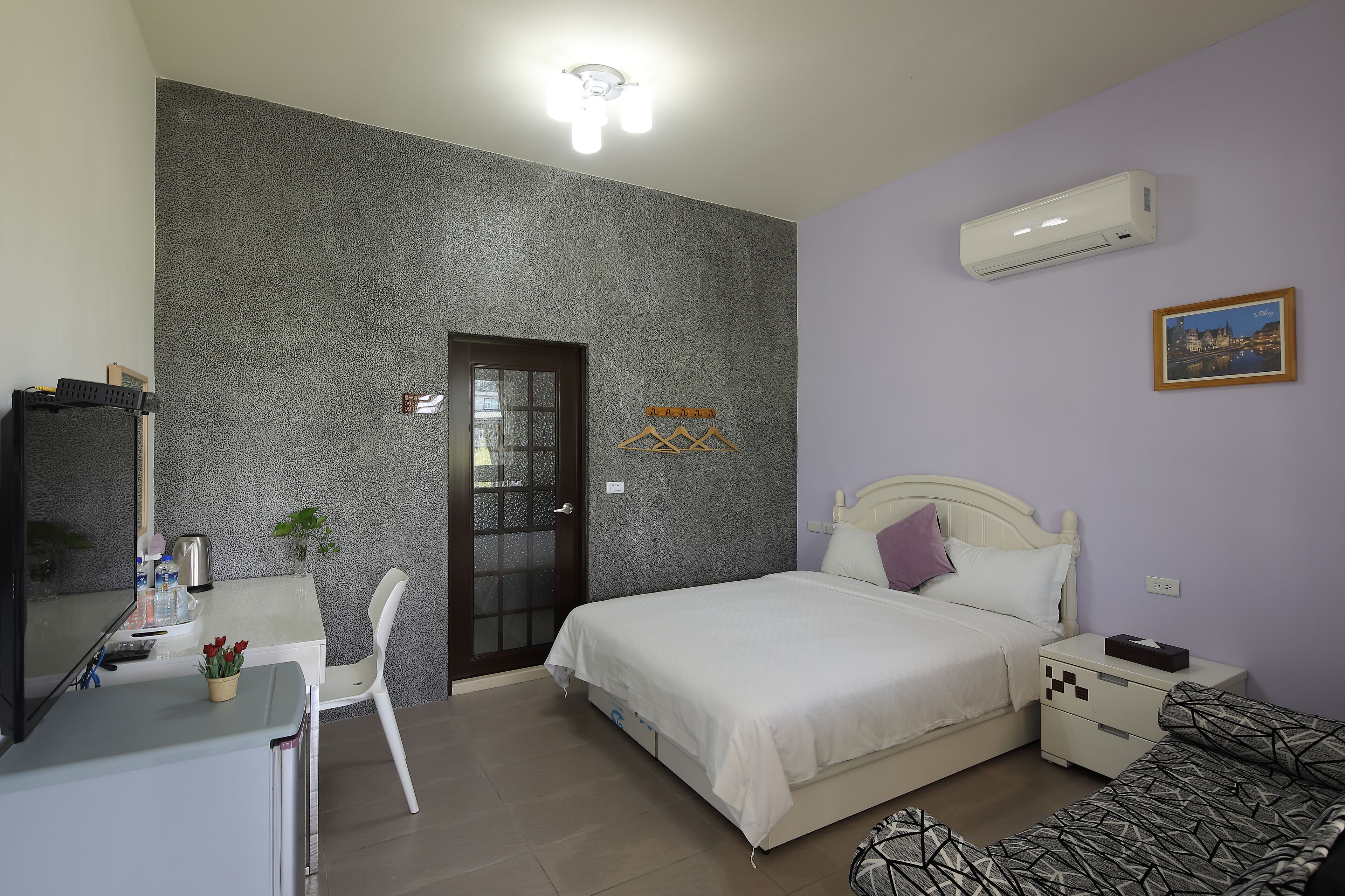 A bedroom with a bed, bedside table, and a desk with a chair.