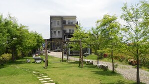 A residential building with a two-story structure, a front yard with a swing set, and a stone pathway leading to the entrance. - Langkawi Garden B&B (Luodong)