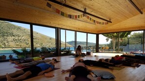 Amplia habitación con ventanas grandes que ofrecen vistas a un lago y colinas.