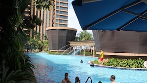 A swimming pool with people, surrounded by palm trees and modern buildings. - Sky Apartment at Times Square (Kuala Lumpur)