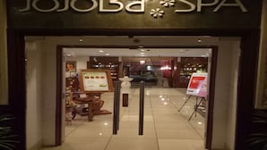 The entrance to JoJoBa Spa with a 'Welcome' mat, a reception desk, and a menu board visible inside. - Sky Apartment at Times Square (Kuala Lumpur)