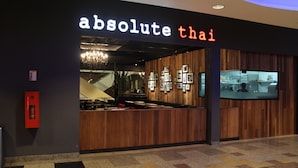 A restaurant named "absolute thai" with a modern interior design, wooden paneling, and a visible kitchen area. - Sky Apartment at Times Square (Kuala Lumpur)