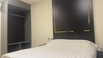 A bedroom with a bed, a wardrobe, and a wall-mounted TV.