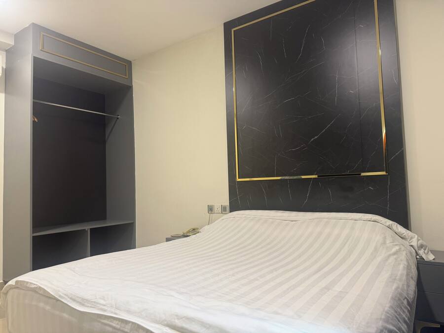 A bedroom with a bed, a wardrobe, and a wall-mounted TV.