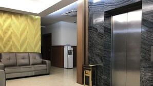 A lobby with a sofa, a water dispenser, and an elevator. - Aeton Hotel (Nilai)