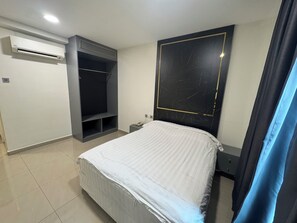 A bedroom with a bed, a wardrobe, an air conditioning unit, and a marble-patterned headboard. - Aeton Hotel (Nilai)
