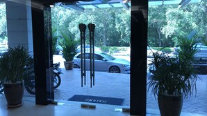 A hotel entrance with a glass door, potted plants, and a parking area visible through the door. - Aeton Hotel (Nilai)