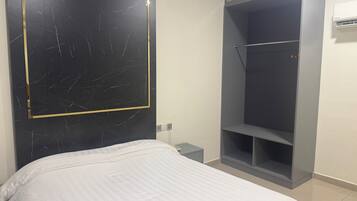 Un dormitorio con cama, armario y aire acondicionado de pared.