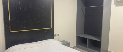 Un dormitorio con cama, armario y aire acondicionado de pared.