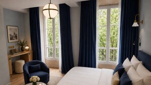 Een slaapkamer met een groot bed, een bureau, een stoel en een raam met gordijnen.