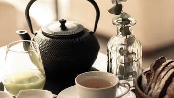 A tea set with a teapot, cups, saucer, and a glass of tea on a table.