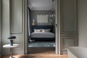 A bedroom with a bed, a round table, and a hanging light fixture.