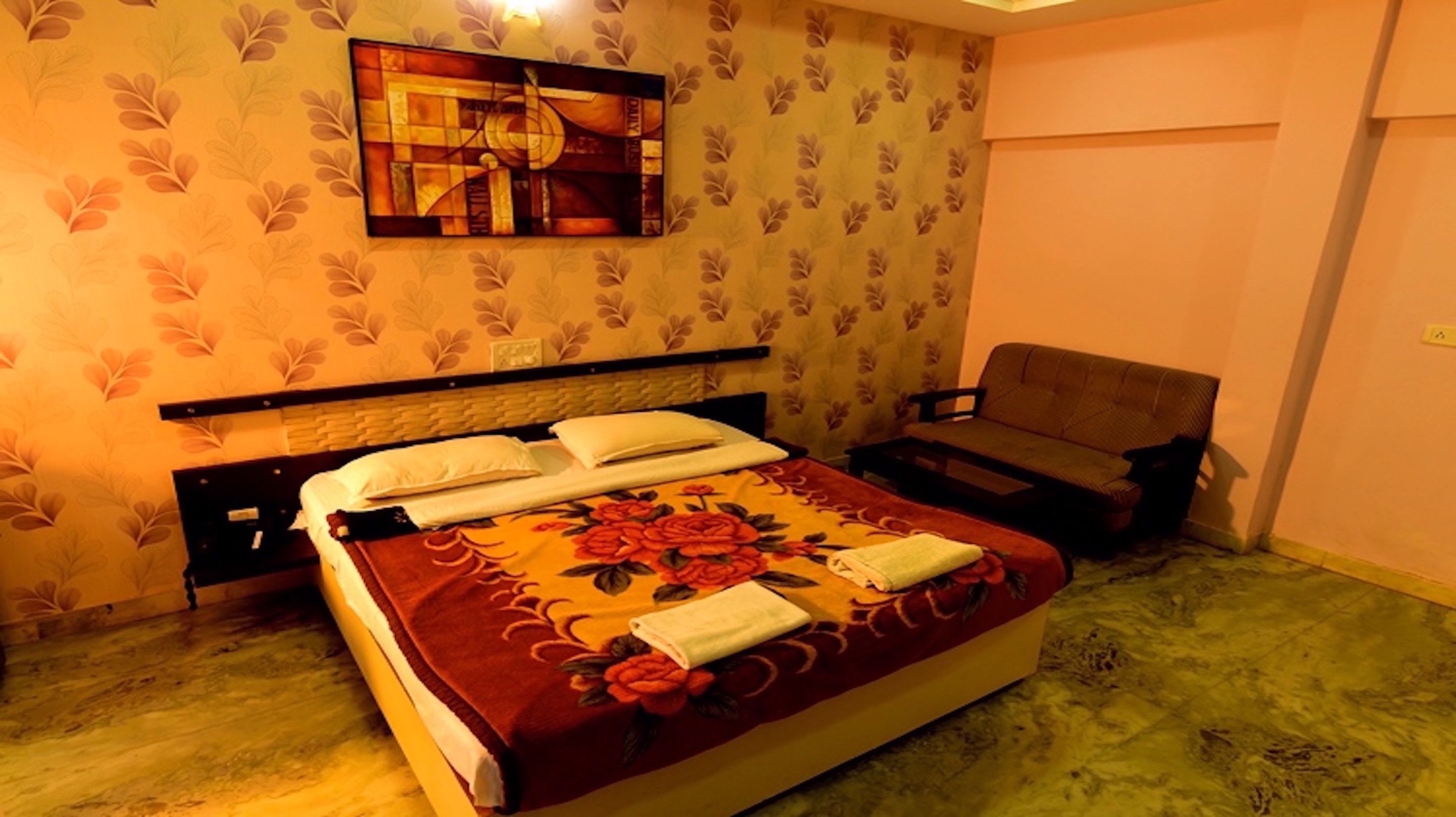 A hotel room with a bed, a bench, and a wall-mounted artwork.