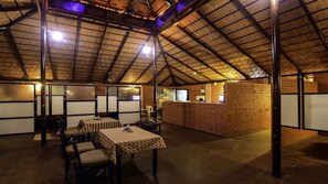 A spacious dining area with high ceilings and exposed beams, featuring a brick counter and traditional Japanese sliding doors. - Hotel Ashlesh (Udupi)