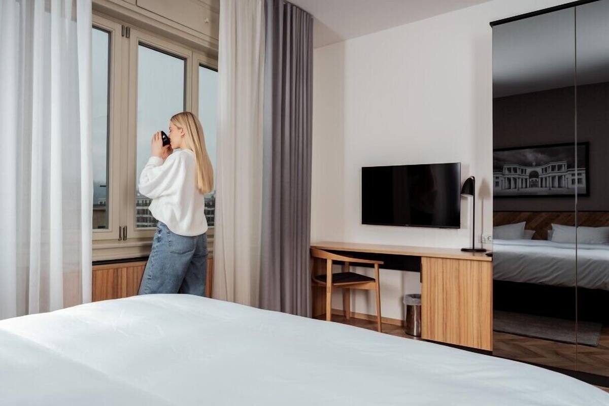 Una habitación de hotel con cama, escritorio, silla, televisión y un ventanal grande.