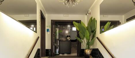 Una escalera con peldaños cubiertos de moqueta negra y peldaños de granito, que conduce a una zona de cocina.