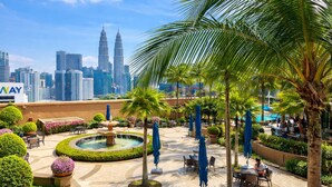 A hotel courtyard with a fountain, palm trees, and outdoor seating. - KL Bintang Suites at Times Square (Kuala Lumpur)