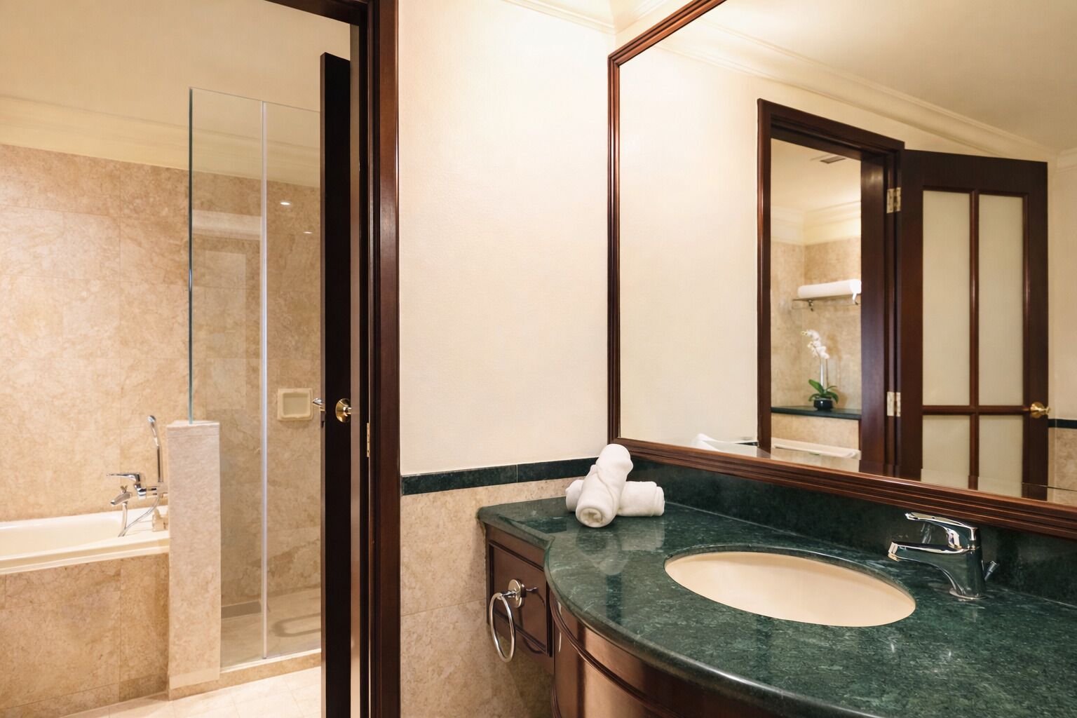 Un baño con cabina de ducha de vidrio, un lavabo con encimera de mármol y un espejo grande.