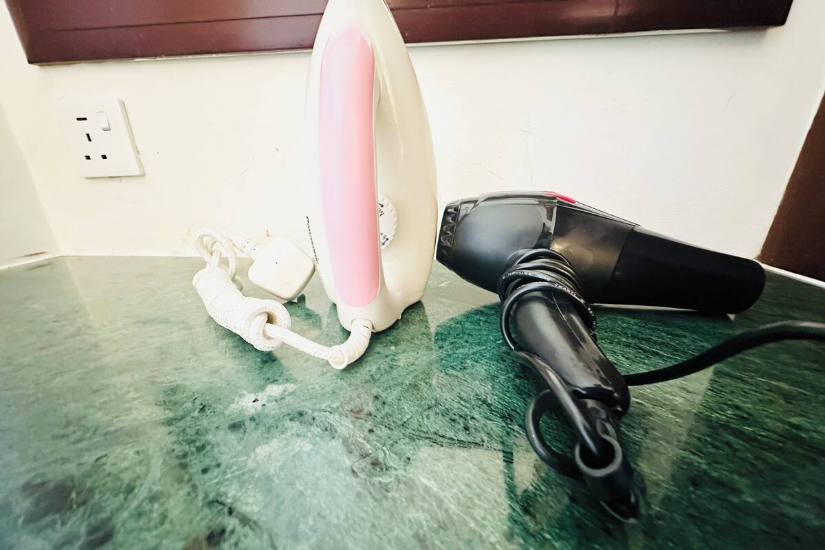 Ein Haartrockner und ein Lockenstab liegen auf einer grünen Arbeitsplatte.