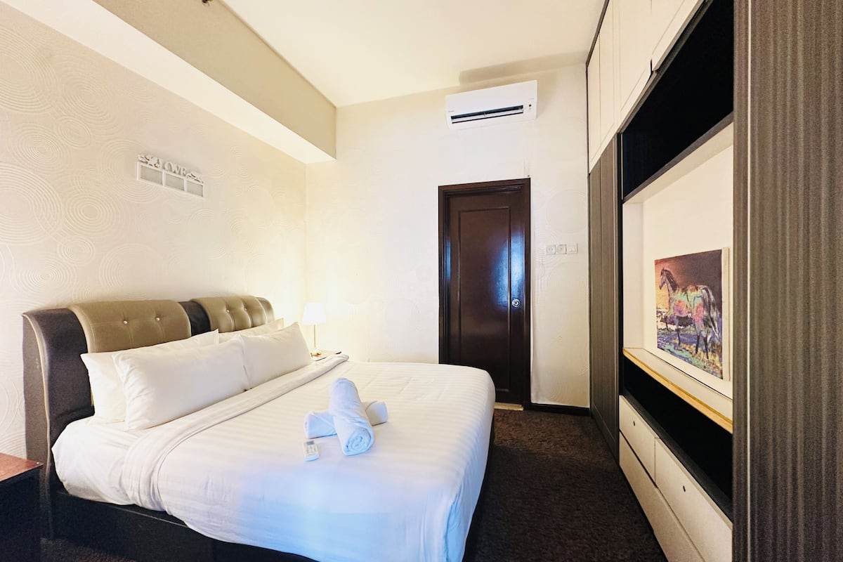 Ein Hotelzimmer mit einem Bett, einer Wand-Klimaanlage, einer Tür und einem gerahmten Gemälde an der Wand.