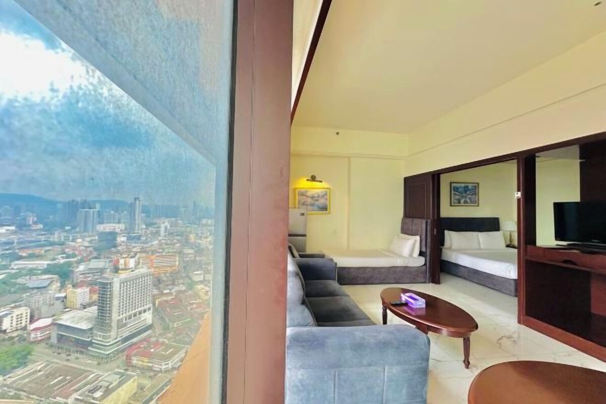 A modern hotel room with a city view, a sofa, a bed, and a TV.