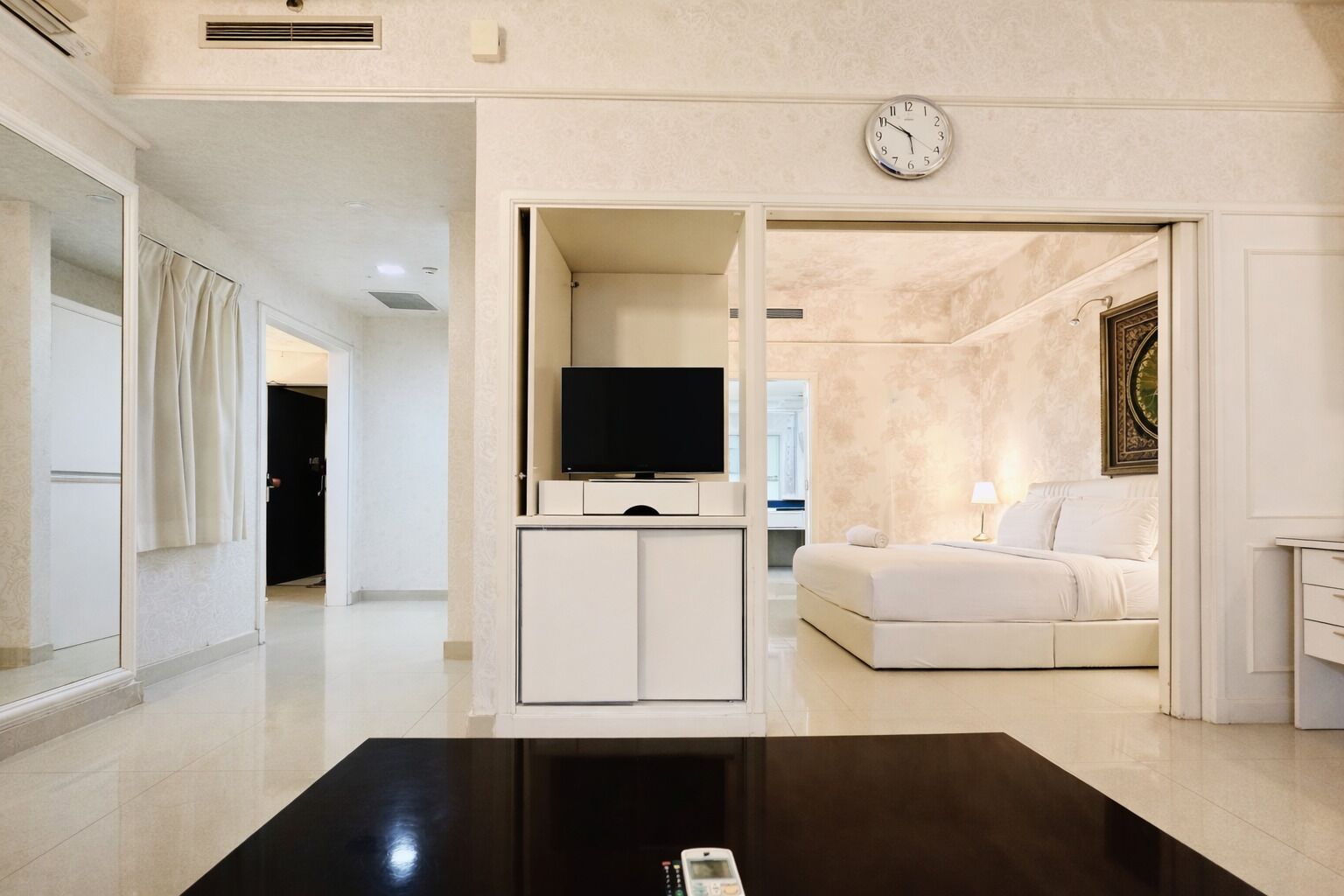 Une chambre d’hôtel moderne équipée d’une télévision à écran plat, d’un canapé, d’une table de chevet et d’une horloge murale.