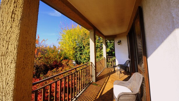 A balcony with a view of autumn foliage, a wicker chair, and a small table. - Bed & Breakfast La Dimora di Garlasco (Garlasco)