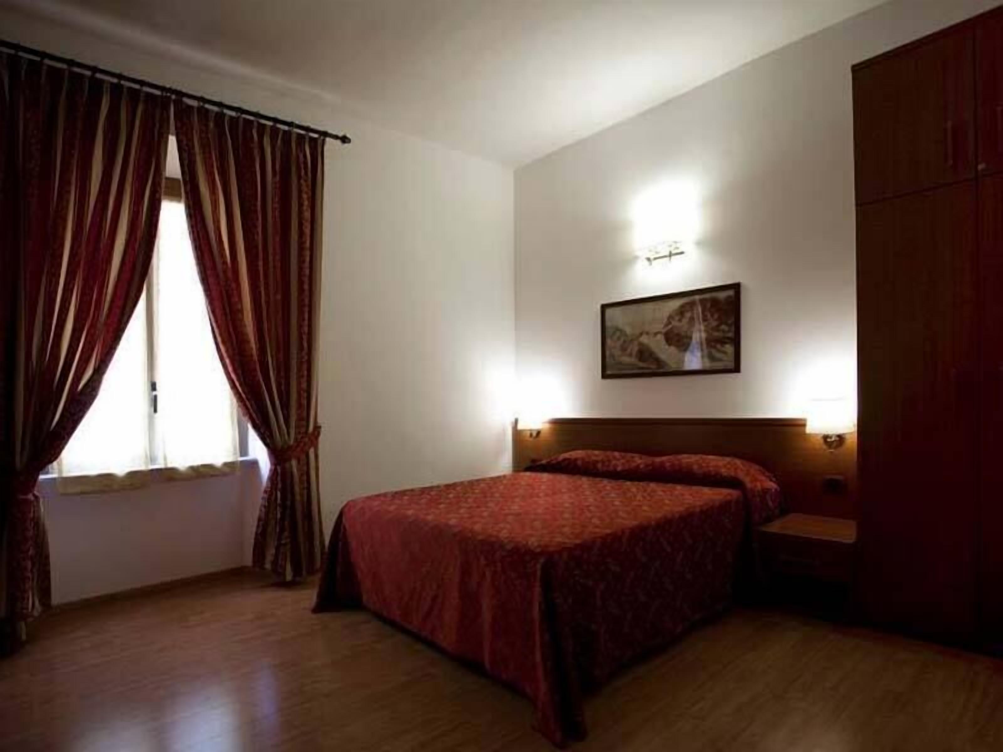 A hotel room with two single beds, a wooden floor, a large wardrobe, and a painting on the wall.