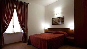 A hotel room with two single beds, a wooden floor, a large wardrobe, and a painting on the wall.