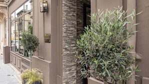 A building facade with a stone wall, a door, and a potted plant. - Hôtel Churchill (Bordeaux)