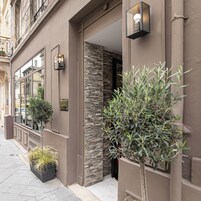 Fachada de edificio con pared de piedra, una puerta y una planta en maceta.